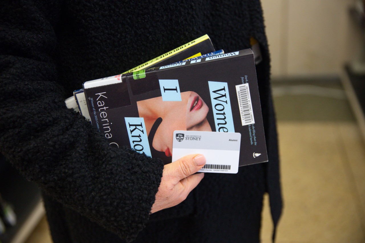 Person holding books and Alumni Library membership card